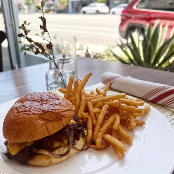 A burger with cheese and caramelized onions, served with a side of golden french fries.
