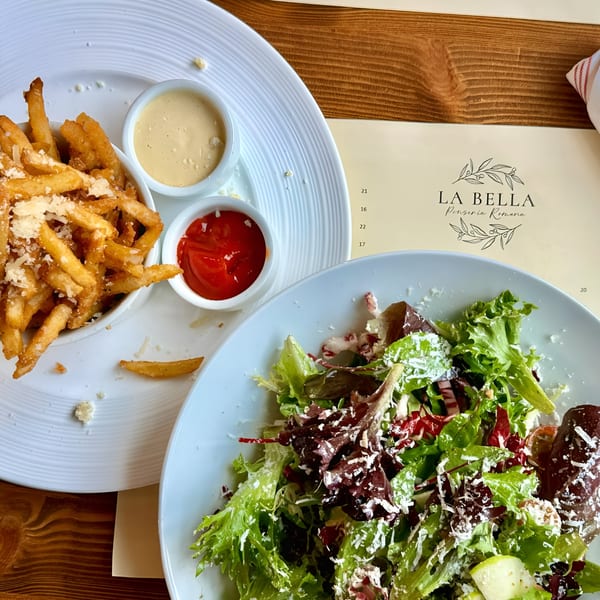 La Bella Pinseria Romana's parmesan fries with ketchup and aioli, alongside a fresh green salad.
